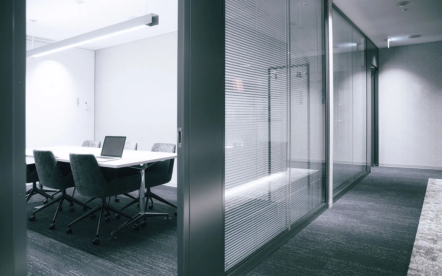 Meeting room behind glass walls fitted with fine venetian blinds