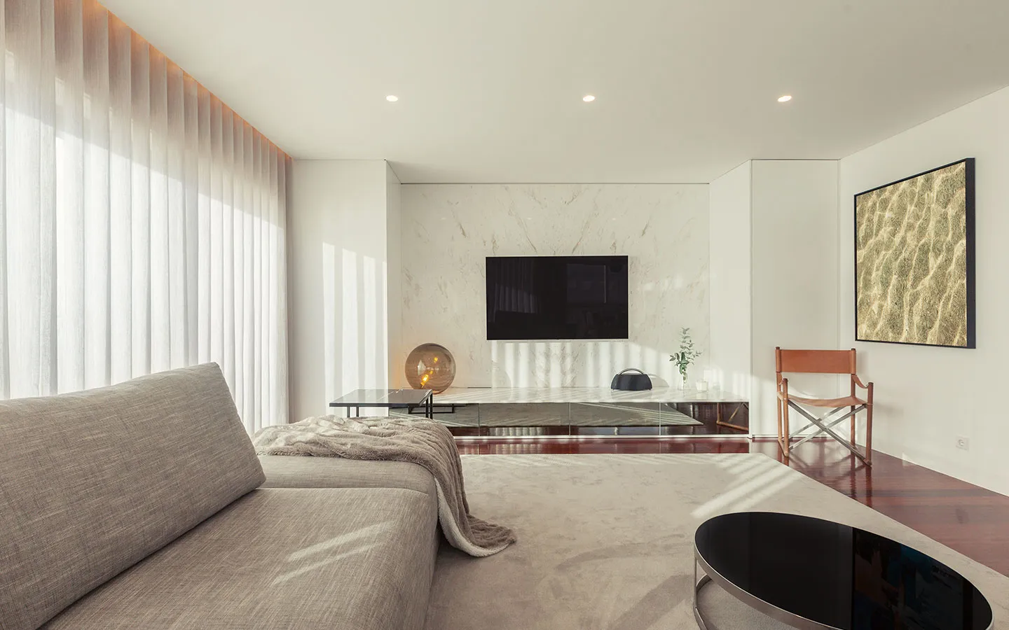 Lounge with soft white sheer curtains along a full-height window wall
