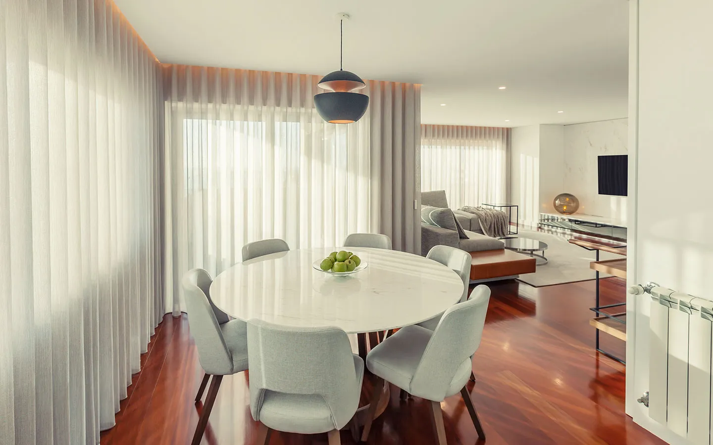 Living room with a floor-to-ceiling grey curtain beside glass walls overlooking a pool
