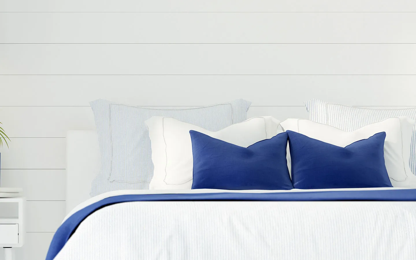 Bed dressed with blue cushions and striped white pillows